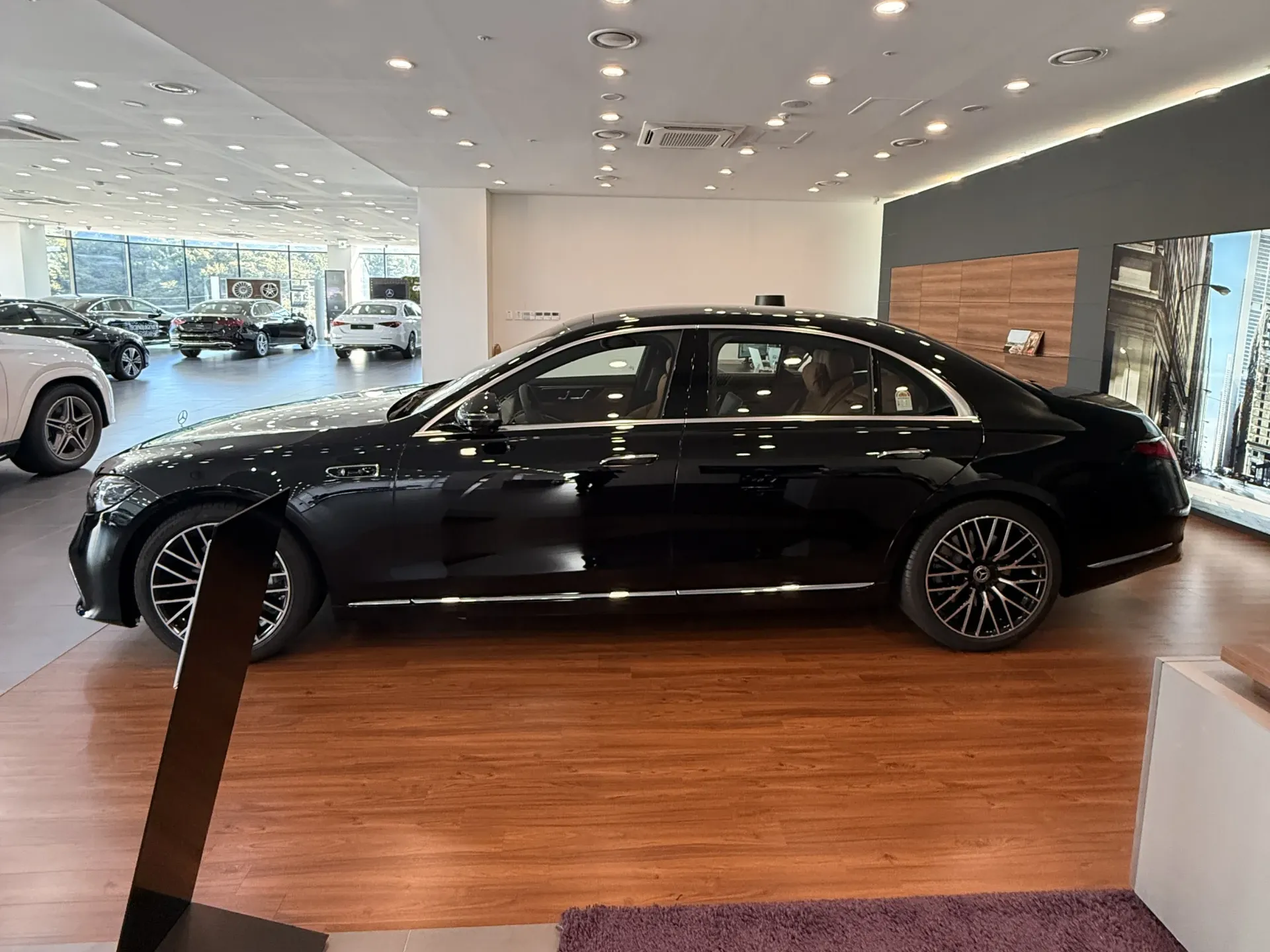 전시대 옆에 선 검은색 신형 벤츠 S500 세단 측면 전체
