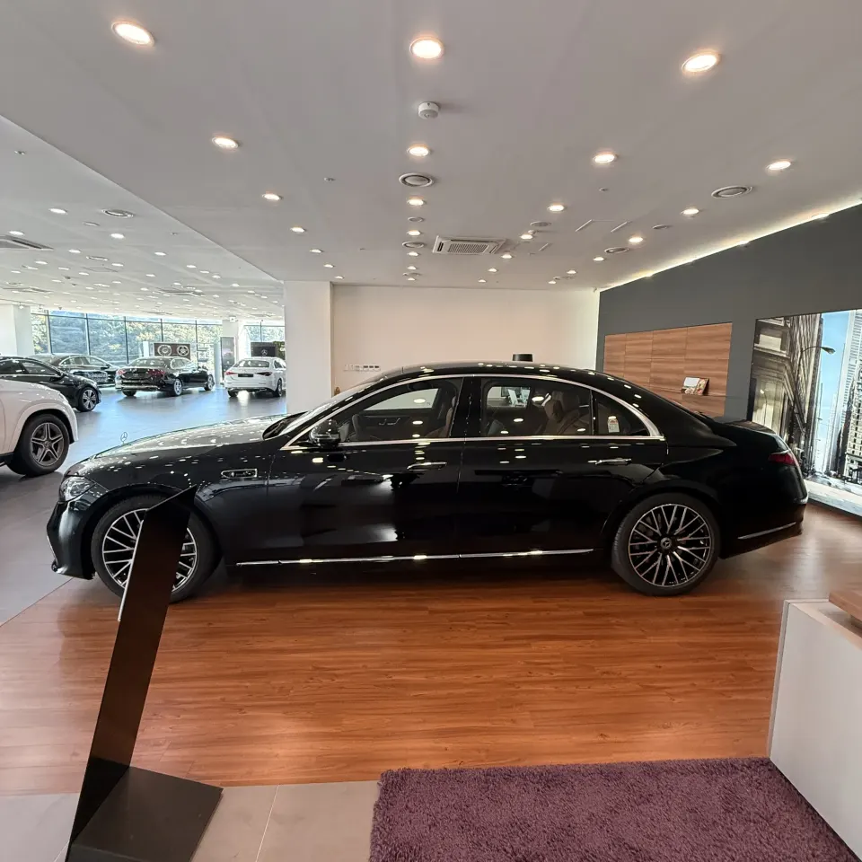 전시대 옆에 선 검은색 신형 벤츠 S500 세단 측면 전체